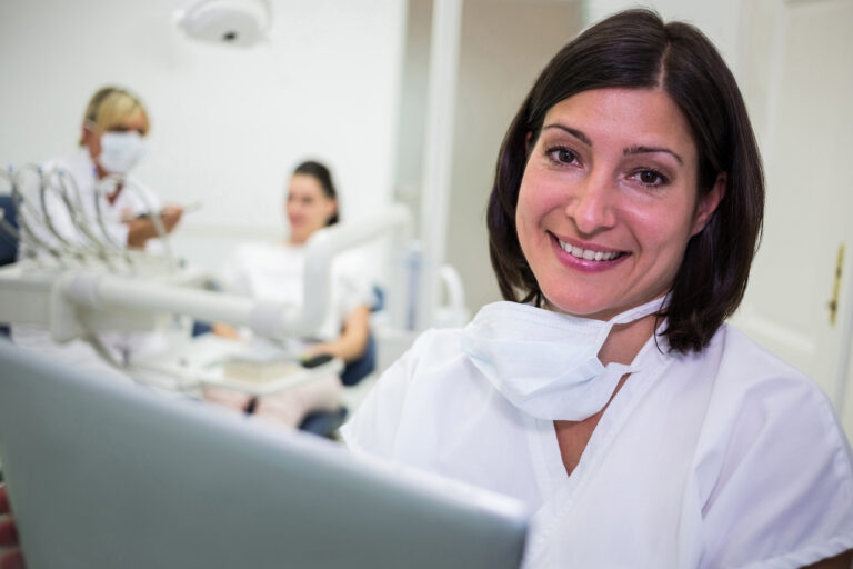Confident businesspeople standing outside office building with laptop